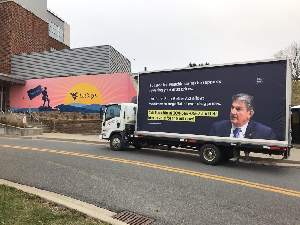 1386 Mobile billboard with message calling on Senator Joe Manchin of West Virginia to vote for lower drug prices by passing the Build Back Better Act.